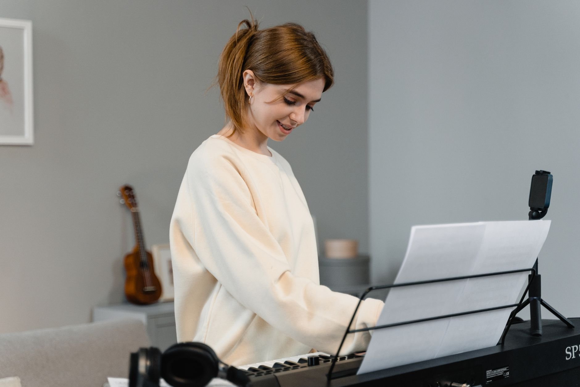 Young woman playing an electric piano, smiling while reading sheet music