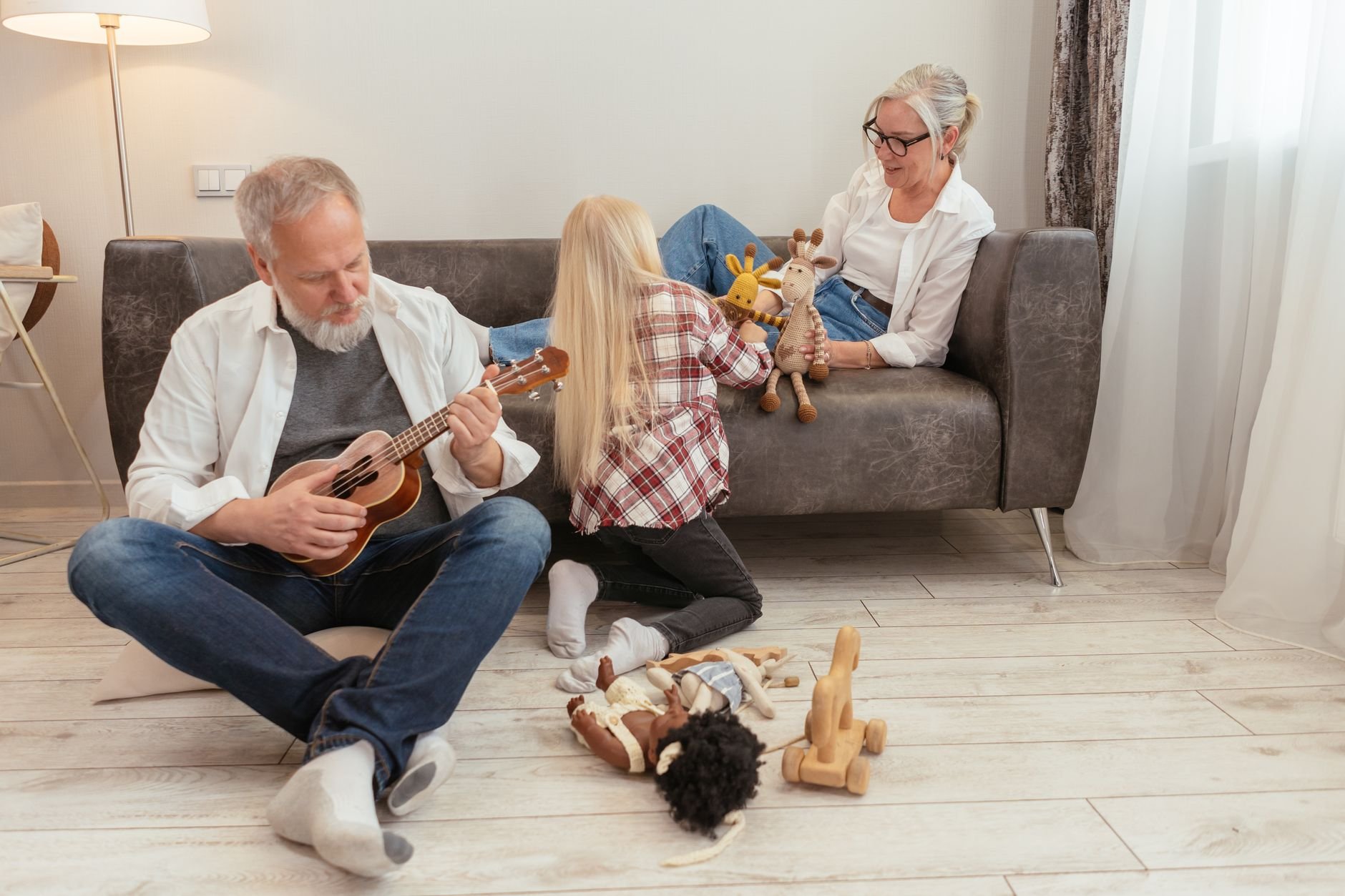 Grandparents and grandchild playing ukulele together on a cosy sofa
